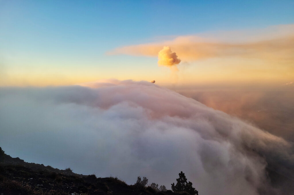 Sonnenaufgang mit Blick auf ausbrechenden Vulkan Fuego bei Acatenango Wanderung