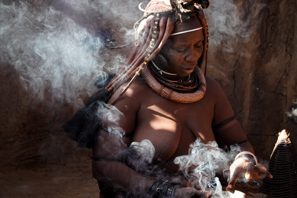Himba Frau bei traditioneller Räucherreinigung